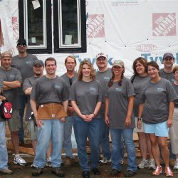 a group of people standing in front of an unfinished house looking like they are working on the house